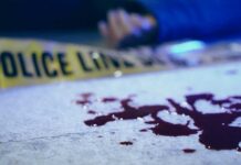 Midtown Platform Chaos – One Shot, One Dead Blood on pavement with police tape and a hand in the background
