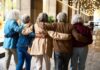 Group of elderly friends walking arm in arm outdoors