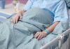 Patient resting in a hospital bed with hands on blanket