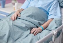 Patient resting in a hospital bed with hands on blanket