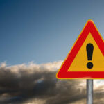 Midair Mystery – Six Vanish A triangular warning sign with an exclamation mark against a cloudy sky
