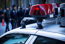 Baby Killed, AG Clears Police car roof with lights, officers in background.