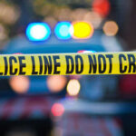 River Deaths Spark Serial Killer Fears Police tape and lights at crime scene.