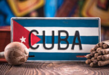 A decorative Cuban license plate with a maraca and a bundle of cigars