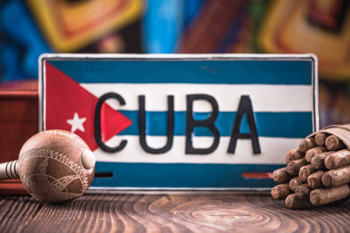 Travel,To,Cuba,Concept,,Related,Items. A decorative Cuban license plate with a maraca and a bundle of cigars